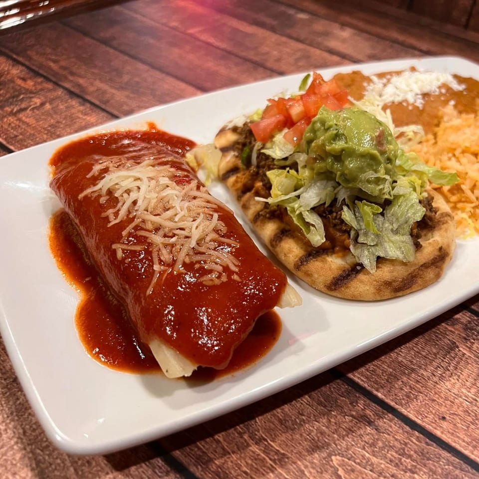 A La Casona Mexican Restaurant plate with a red enchilada, a sope, rice, and beans.